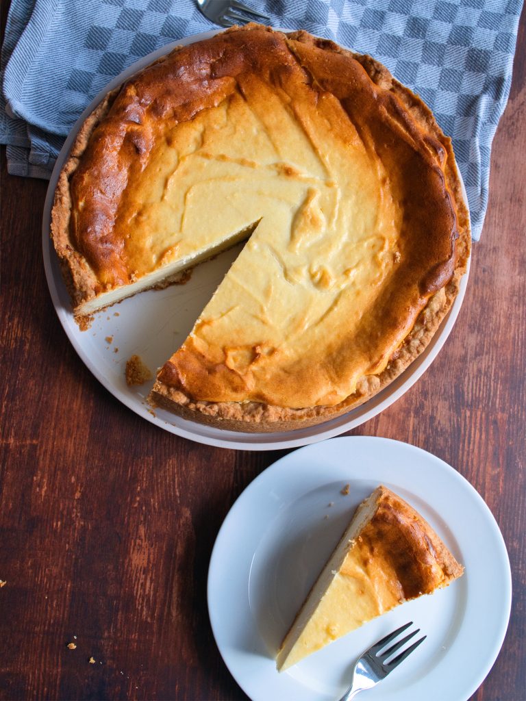 Ein Stüc Käsekuchen und ein angeschnitter Käsekuchen auf Tellern.