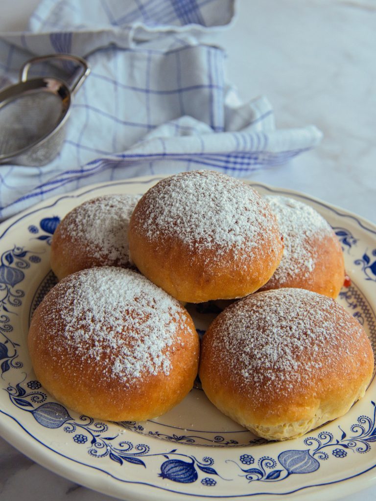 Fünf Krapfen auf einem Teller mit Puderzucker
